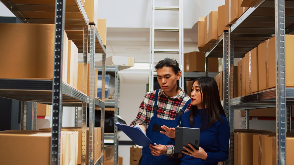 asian employees checking warehouse supplies tablet files working with storage room logistics young team people using gadget papers business plan production